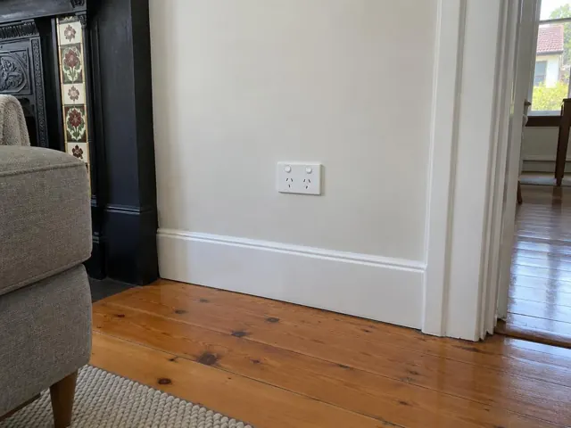 White double power point on a painted wall above skirting in a timber-floored living room in Roseville