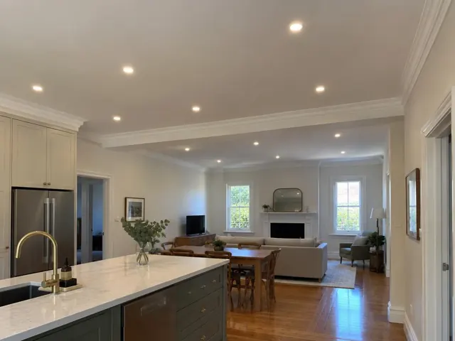 Ceiling downlights in open-plan kitchen and living room with timber floors and fireplace in Killara